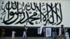 A vendor selling Taliban flags waits for customers next to a large Taliban flag in Kabul on Sept. 24, 2021. 