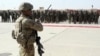 FILE - U.S. military personal stands guard during a graduation ceremony for Afghan troops, in Lashkargah, capital of southern Helmand province, Afghanistan.