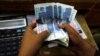 A trader counts Pakistani rupee notes at a currency exchange booth in Peshawar