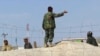 An Afghan soldiers keeps villagers away from a fence at Pakistan-Afghan border post of Chaman